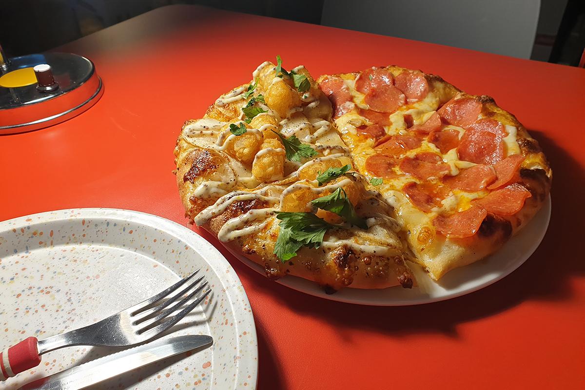 Pizza mezza al pepperoni e mezza al tartufo su un piatto rotondo, sul tavolo di HDD Pizza con un ambiente accogliente.