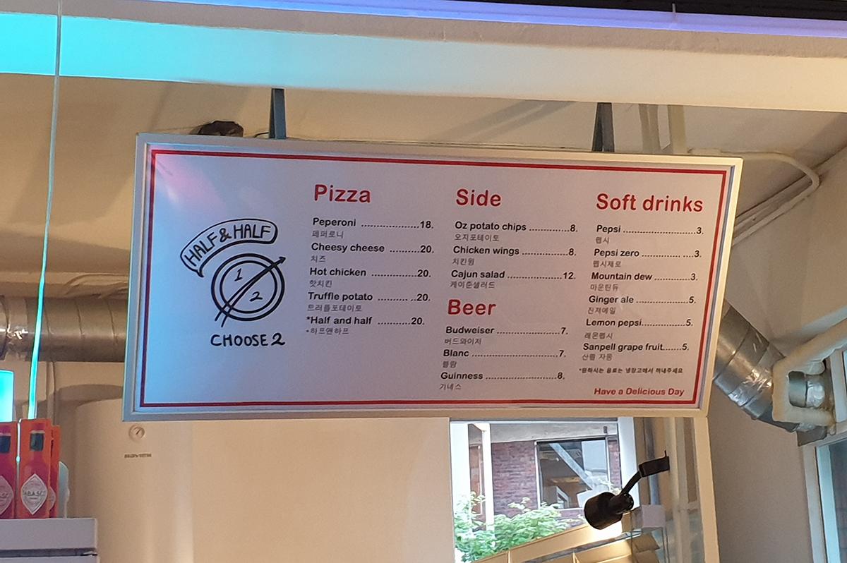 Menù di HDD Pizza appeso all'interno del locale, elencando una varietà di pizze e bevande disponibili.