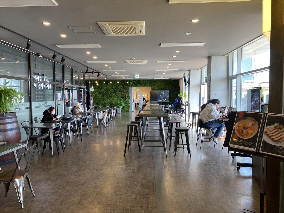 Intérieur du café Caisson 24 avec des tables et des clients profitant d'un repas dans un cadre spacieux.