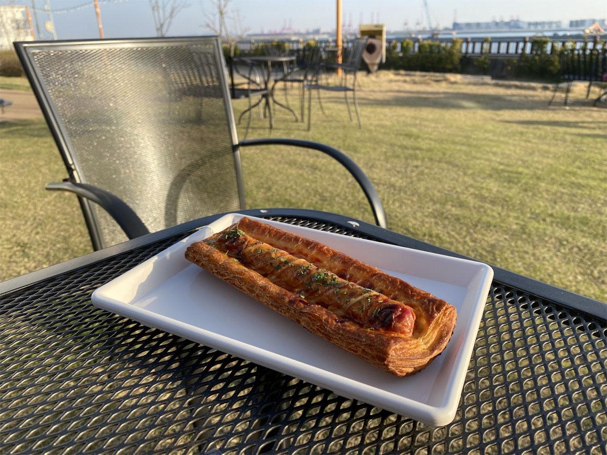 Pâtisserie à la saucisse savoureuse présentée sur une assiette à l'extérieur du café Caisson 24.
