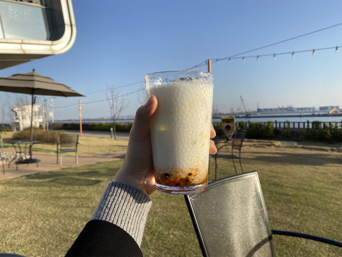 Main tenant un lait sucré aux fruits de la passion sur la terrasse du café Caisson 24.