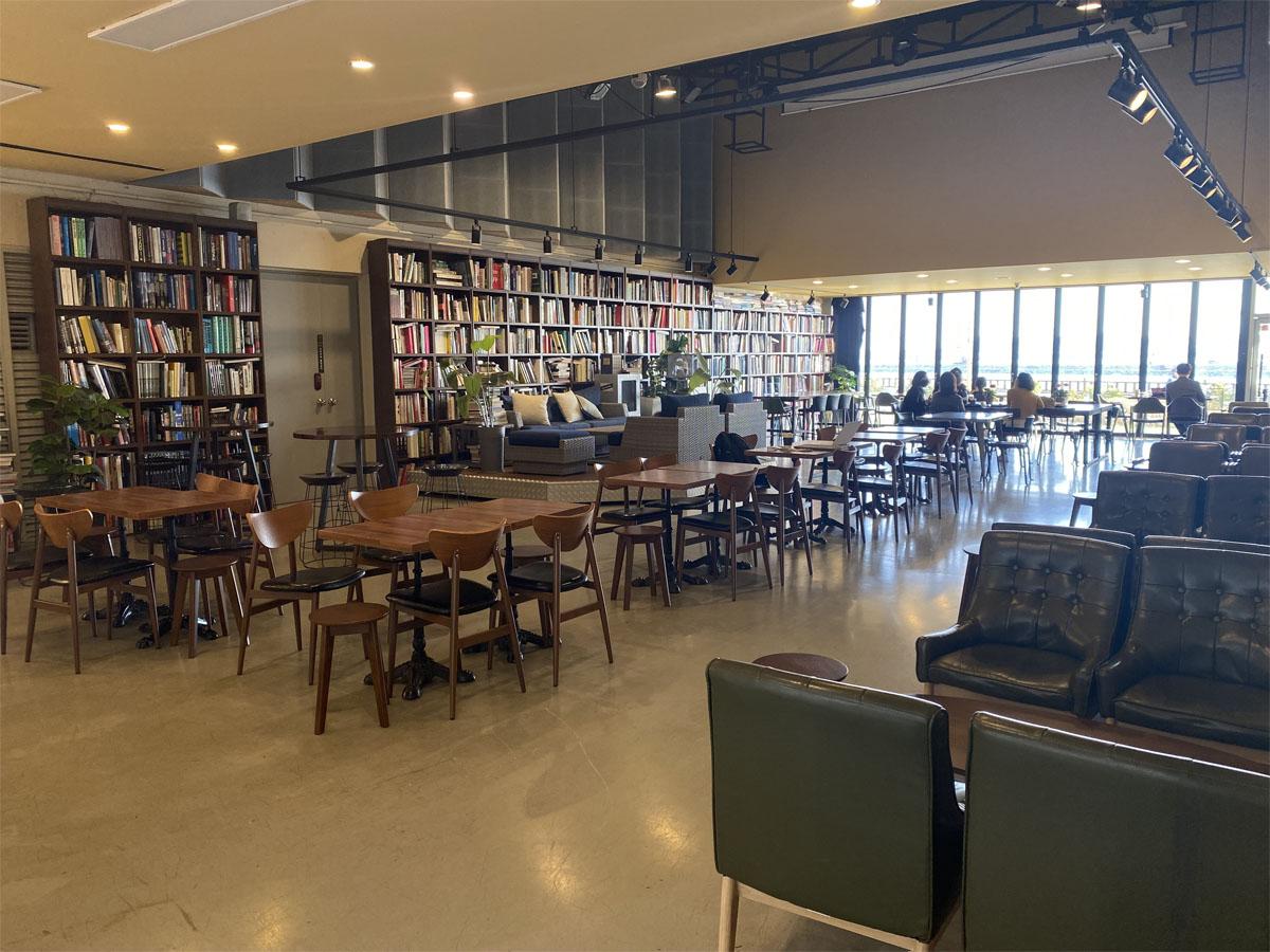 Salle de lecture spacieuse à l'intérieur du café Caisson 24 avec de nombreuses tables et étagères de livres.