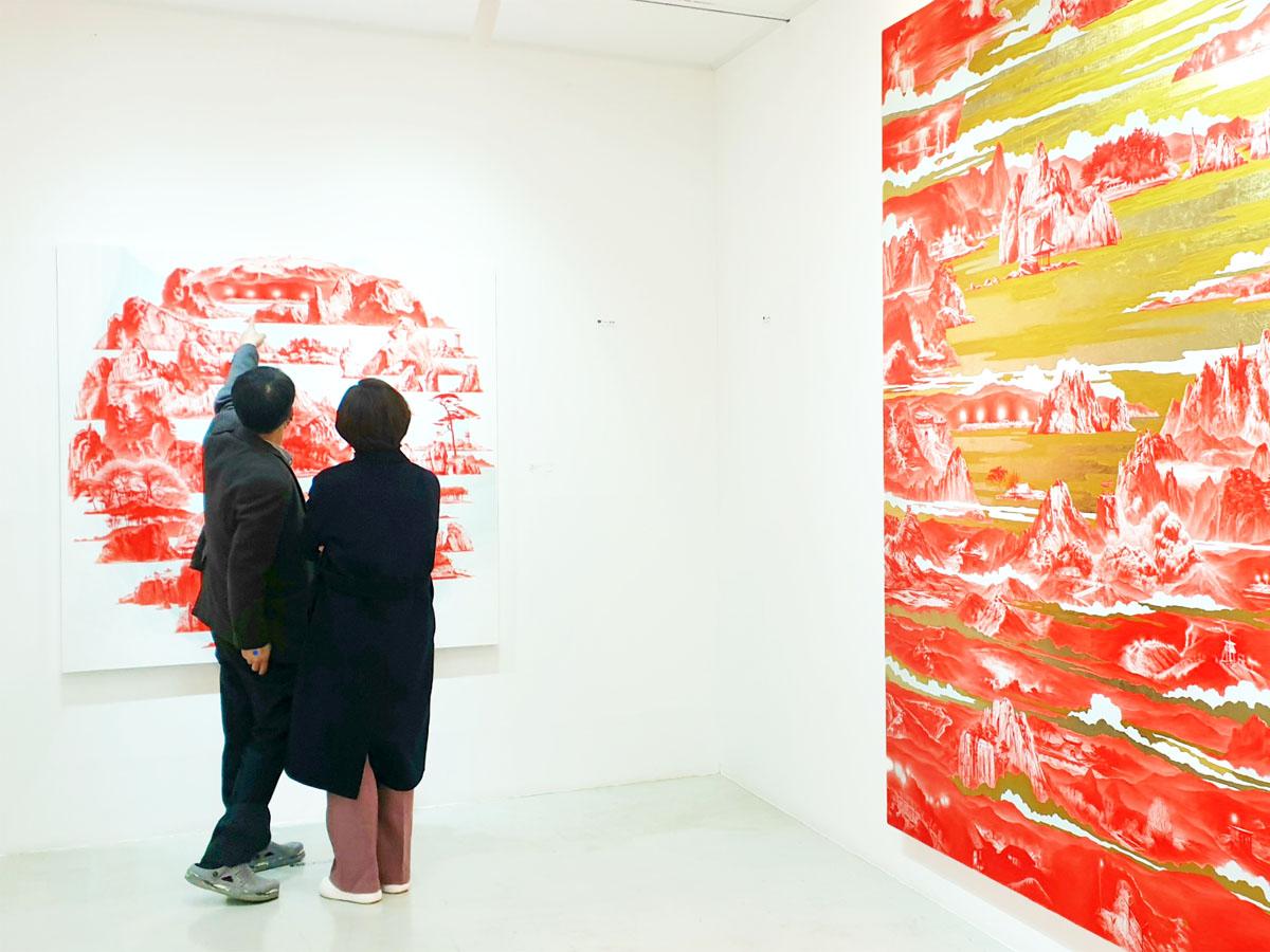 Deux personnes regardant une peinture contemporaine rouge à l'intérieur d'une galerie d'art.