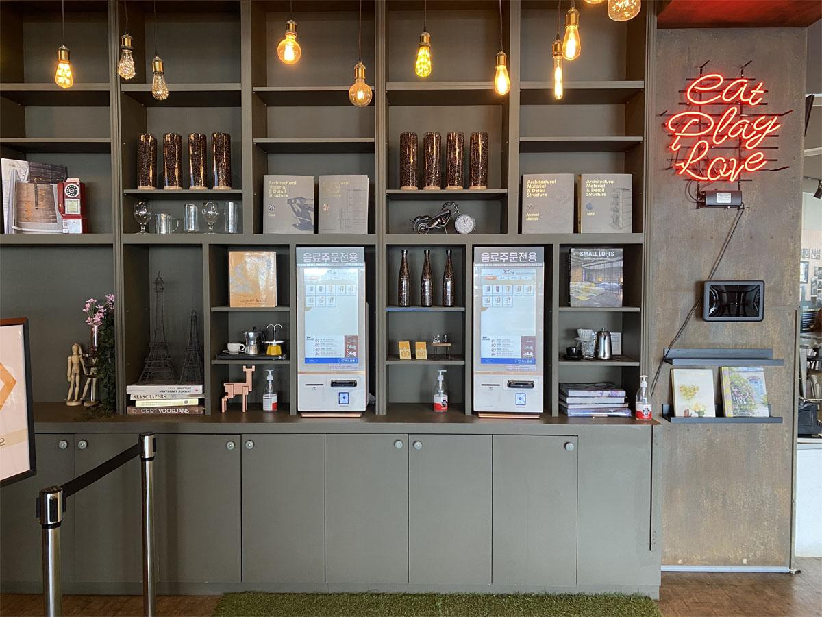 Tableau de boissons au café Caisson 24 avec des articles de souvenir sur l'étagère à droite.