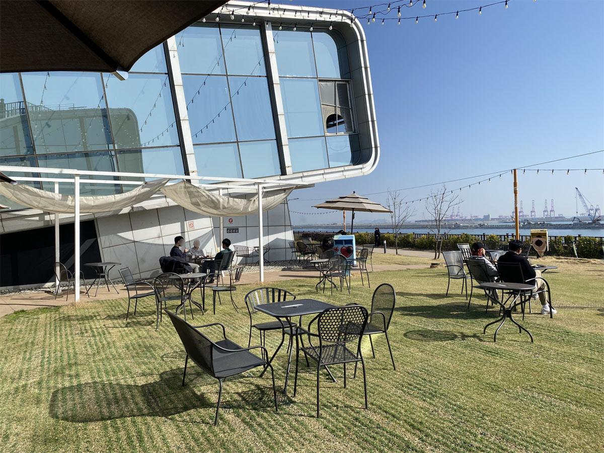 Voûte en verre du café Caisson 24 avec des clients assis à l'extérieur sous un ciel dégagé.