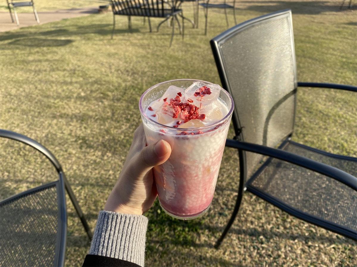 Gros plan d'un latte à la fraise à Caisson 24 avec vue sur l'extérieur.