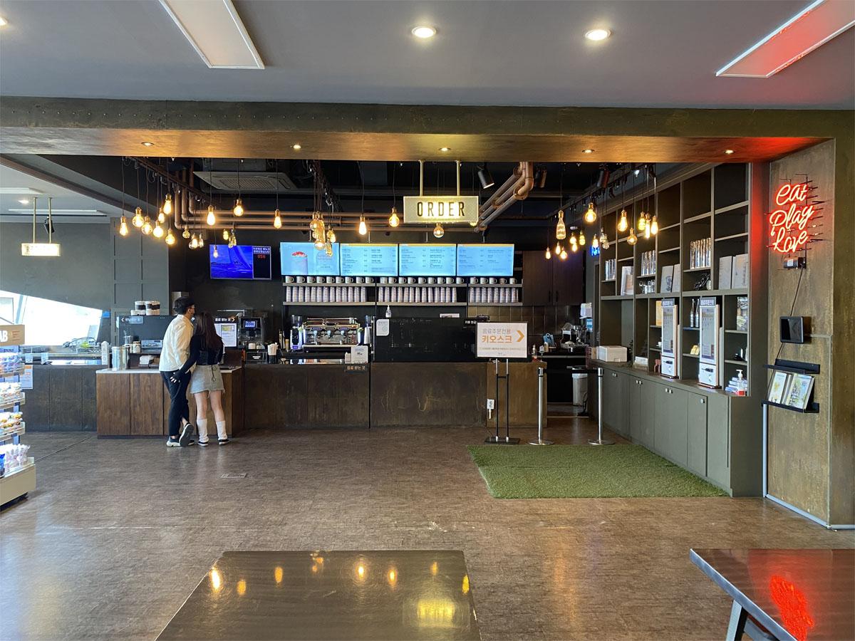 Comptoir de commande de boissons au café Caisson 24 avec un écran de menu lumineux.