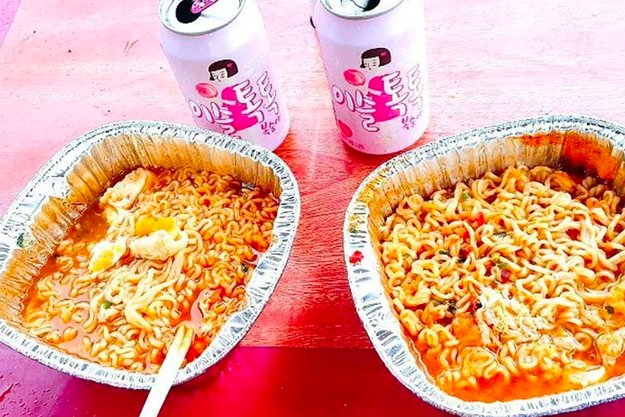 Delicious instant noodles served in aluminum bowls, accompanied by cold drinks, showcasing a popular Korean picnic meal.