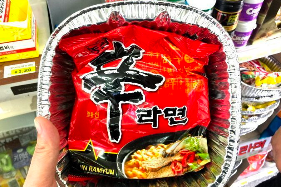 Ramen cups being prepared in a cooking machine, showing noodles boiling and cooking instructions highlighted.