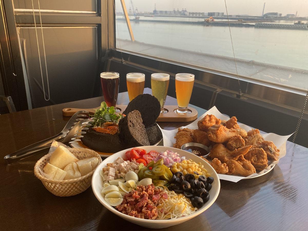 QUIZAS餐厅的多样化美食,包括沙拉、啤酒、炸鸡等,背景是漂亮的海景。