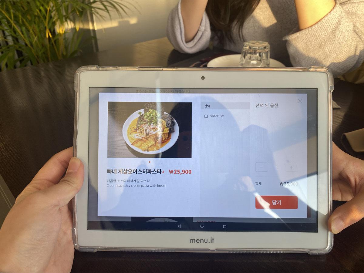 顾客在QUIZAS餐厅使用平板设备点餐,菜单信息清晰易懂,提供多种西式料理选择。