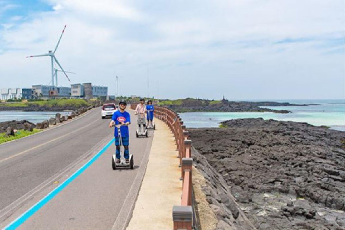 Personas montando segways a lo largo de la carretera costera en Jeju, Corea del Sur