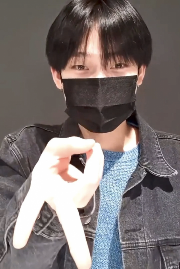 一位穿牛仔外套的男性展示倒V手势,手势靠近镜头成为视觉焦点。