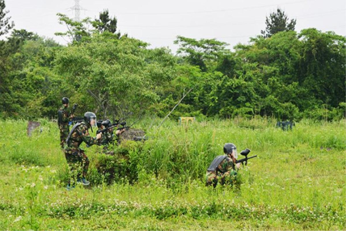 Grupo de personas jugando paintball en un campo verde en Jeju Leports Land.
