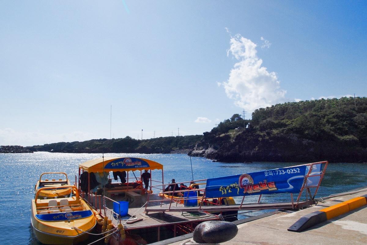 Ein Soesokkak-Jetboot ist im Hafen angedockt, bereit für abenteuerliche Fahrten, mit einem Blick auf die Küste von Jeju Island.