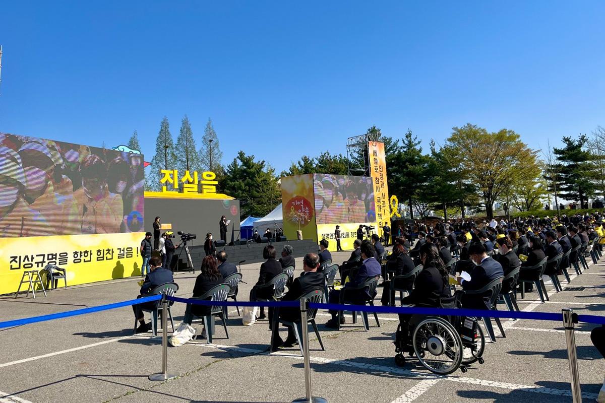 ผู้คนเข้าร่วมพิธีรำลึกเหยื่อเรือเซวอลที่จัดขึ้นในบริเวณกลางแจ้ง โดยมีการแสดงสัญลักษณ์บนเวที