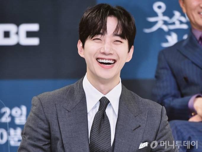 スーツを着た男性、本の表紙には日本語で「俳優イ・ジュノ」