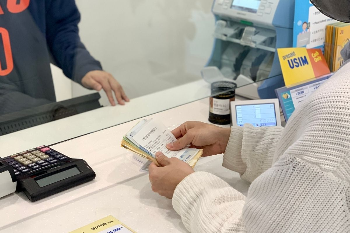 一位顧客在明洞找換店Money Box櫃枱展示匯款單據和現金，顯示換錢過程中的交易細節。