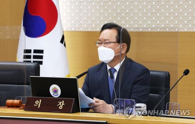 韓国政府の会議室で国旗の前に座り、発言中の官僚。