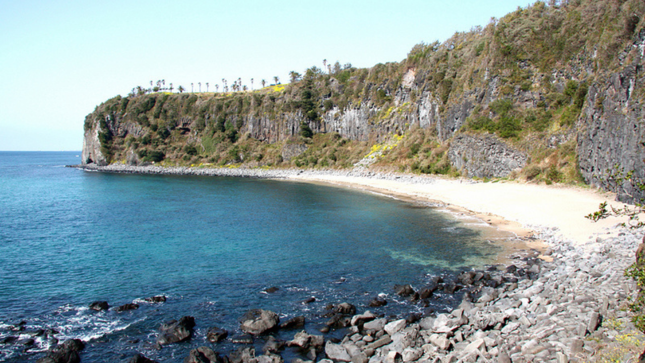 Costa rocciosa di Jeju baciata dalle onde del mare chiaro e limpido