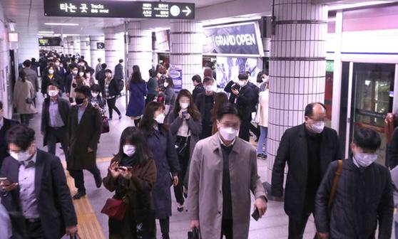 ソウルの地下鉄駅構内で多くの乗客が移動している様子。人々はマスクを着用しており、忙しい通勤時間帯の風景。