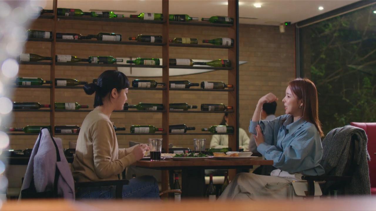 高级餐厅内部场景,两位女士在现代时尚装潢的餐厅酒架前享受轻松愉悦的用餐时刻。