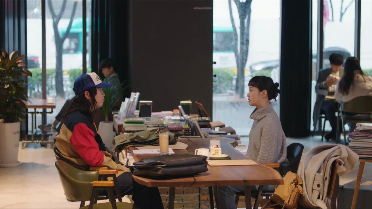现代咖啡厅内,两人在书籍与咖啡的氛围中开展轻松的交流对话,适合悠闲享受午后时光。