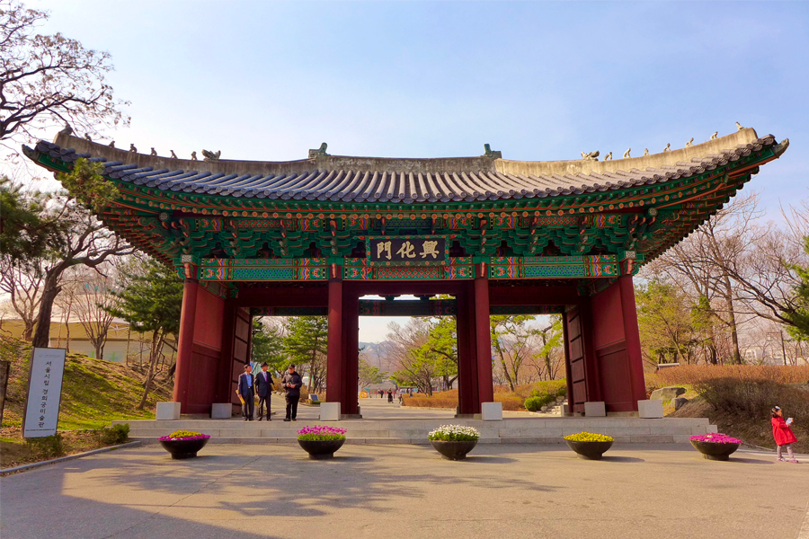 庆熙宫门前庭院的景色，庭院中央种有鲜艳的花坛，历史建筑背景与春天的绿色植物，呈现出祥和的氛围。