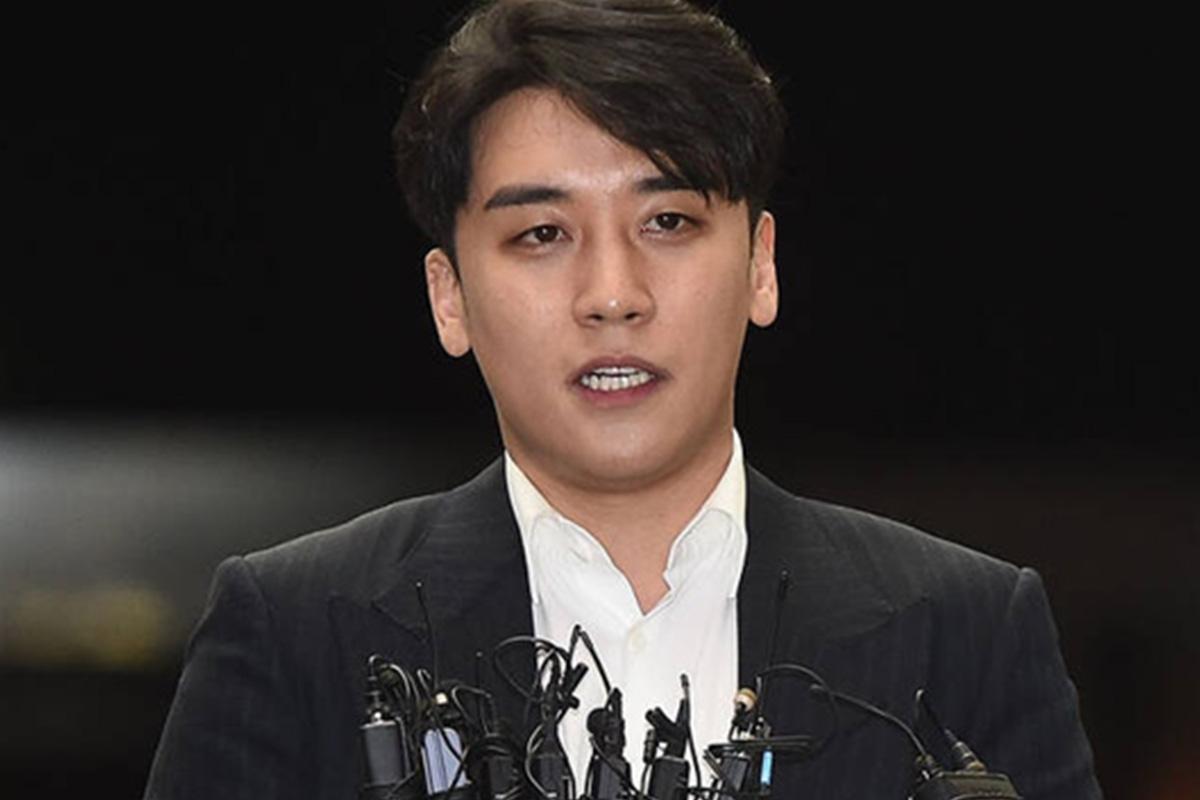 ชายในชุดสูทสีน้ำเงินพูดต่อสื่อมวลชนเกี่ยวกับการพิจารณาคดีในกรณีของ Burning Sun ที่เกาหลีใต้