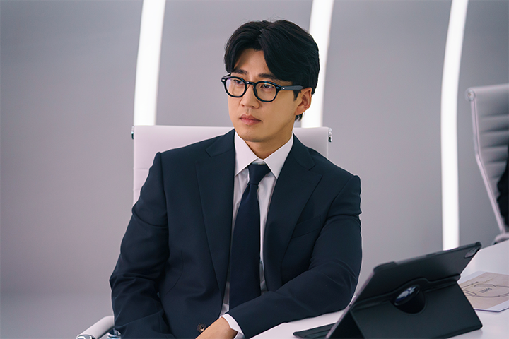 韩国电视剧《第六感之吻》中的会议室场景，一位身穿西装的角色担任会议角色，旁边放着一个平板电脑。