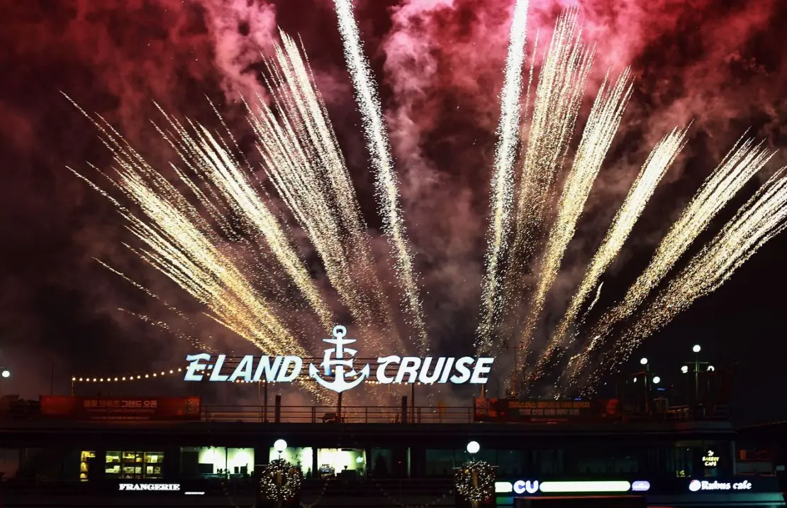 首尔汉江夜间游览船烟火表演，E-LAND CRUISE字样在炫丽的烟火之下显得格外醒目，游客可享受浪漫的汉江夜生活。