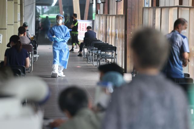 ソウル松坡区の保健所のコロナ19選別診療所での待機中の市民たちと個人防護服を着た医療スタッフ