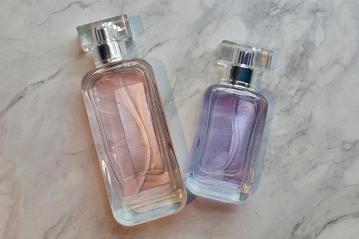 Две парфюмерные бутылки повёрнуты горизонтально, показывающие разницу в цвете содержимого.