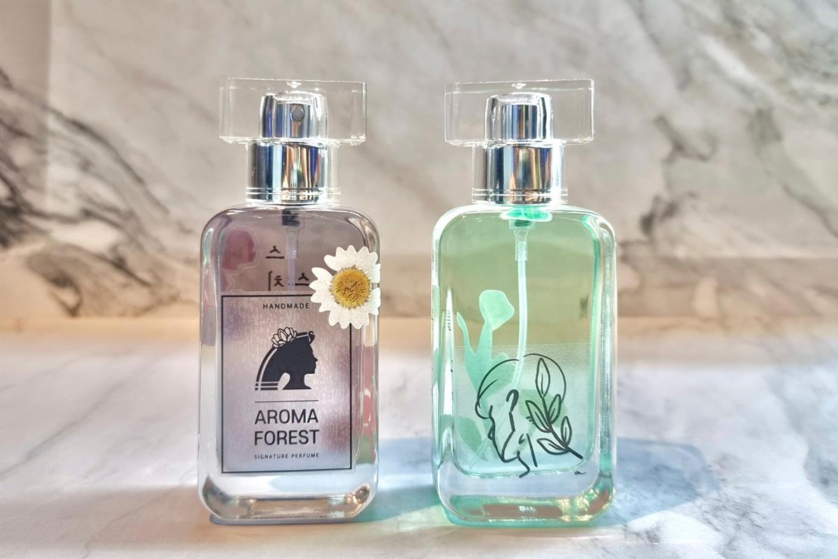 Две готовые бутылки духов из Aroma Forest, одна украшена наклейкой с ромашкой.
