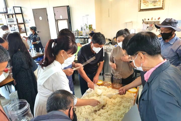 กลุ่มคนกำลังทำข้าวที่มีขนาดใหญ่ ทิวทัศน์ที่บอกเล่าถึงการทำอาหารเกาหลีโบราณและการมีส่วนร่วมที่สนุกสนาน