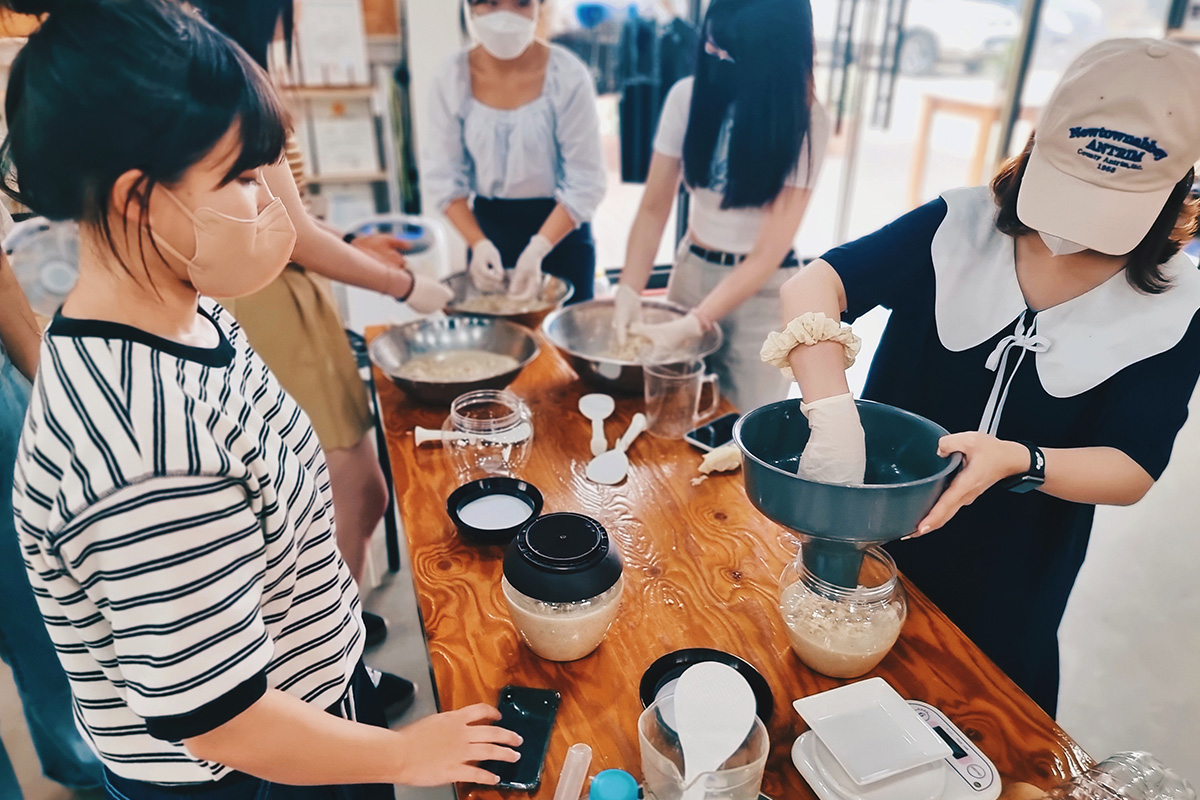 Un groupe de personnes participant à un atelier de brassage de Makgeolli, apprenant le processus dans une ambiance conviviale et pratique.