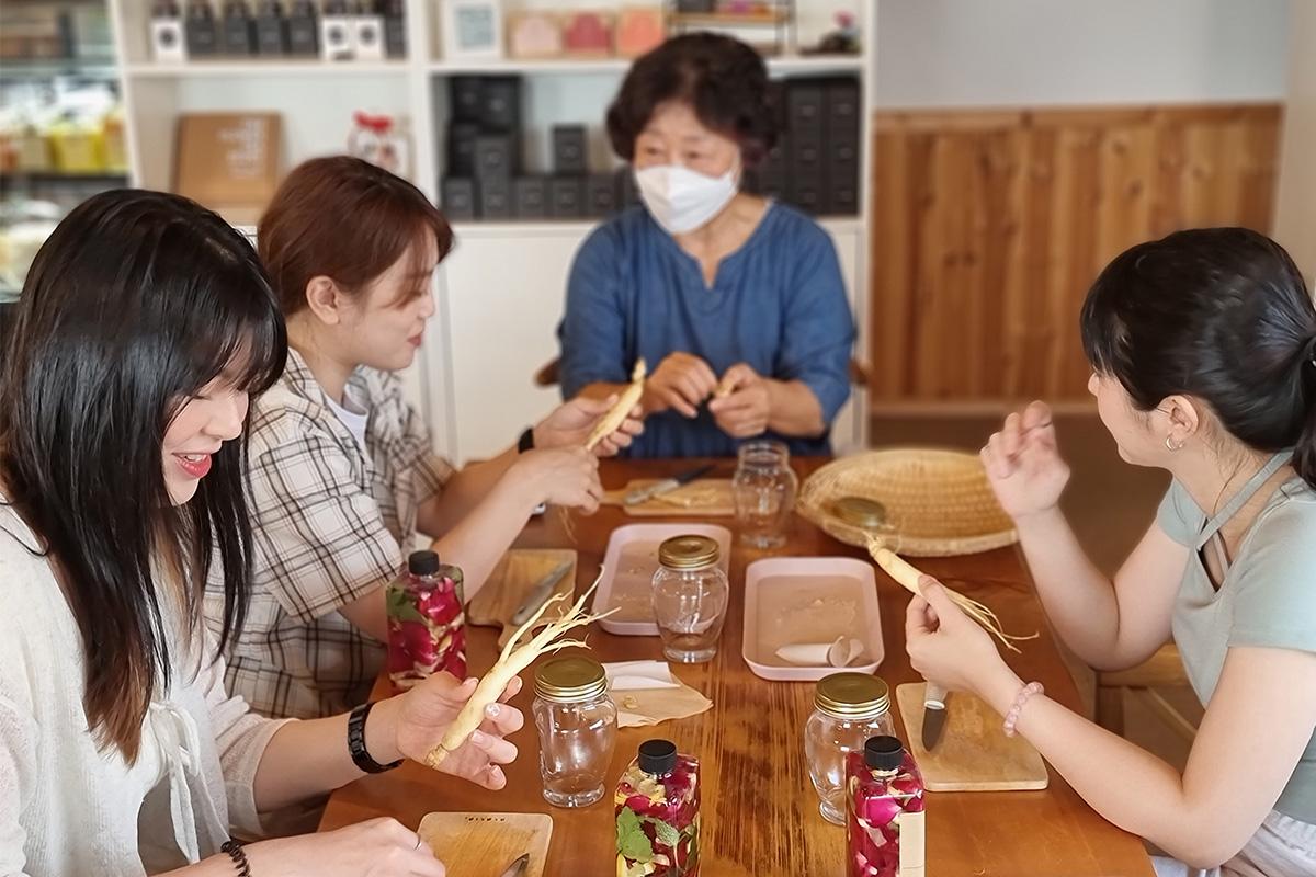 Participants au cours de fabrication de liqueur de ginseng Punggi, concentrés sur l'assemblage des ingrédients.
