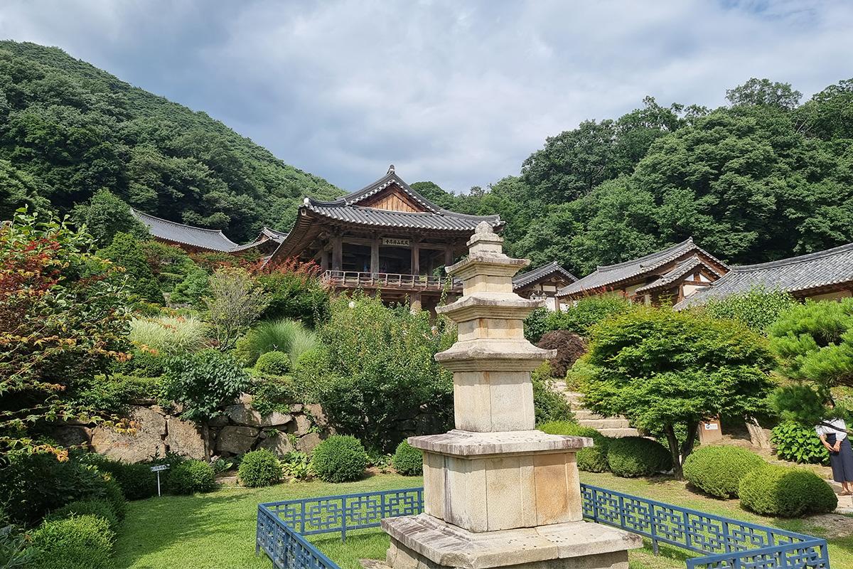 Image du temple Buseoksa, entouré par la nature verdoyante et sous un ciel nuageux en Corée du Sud.