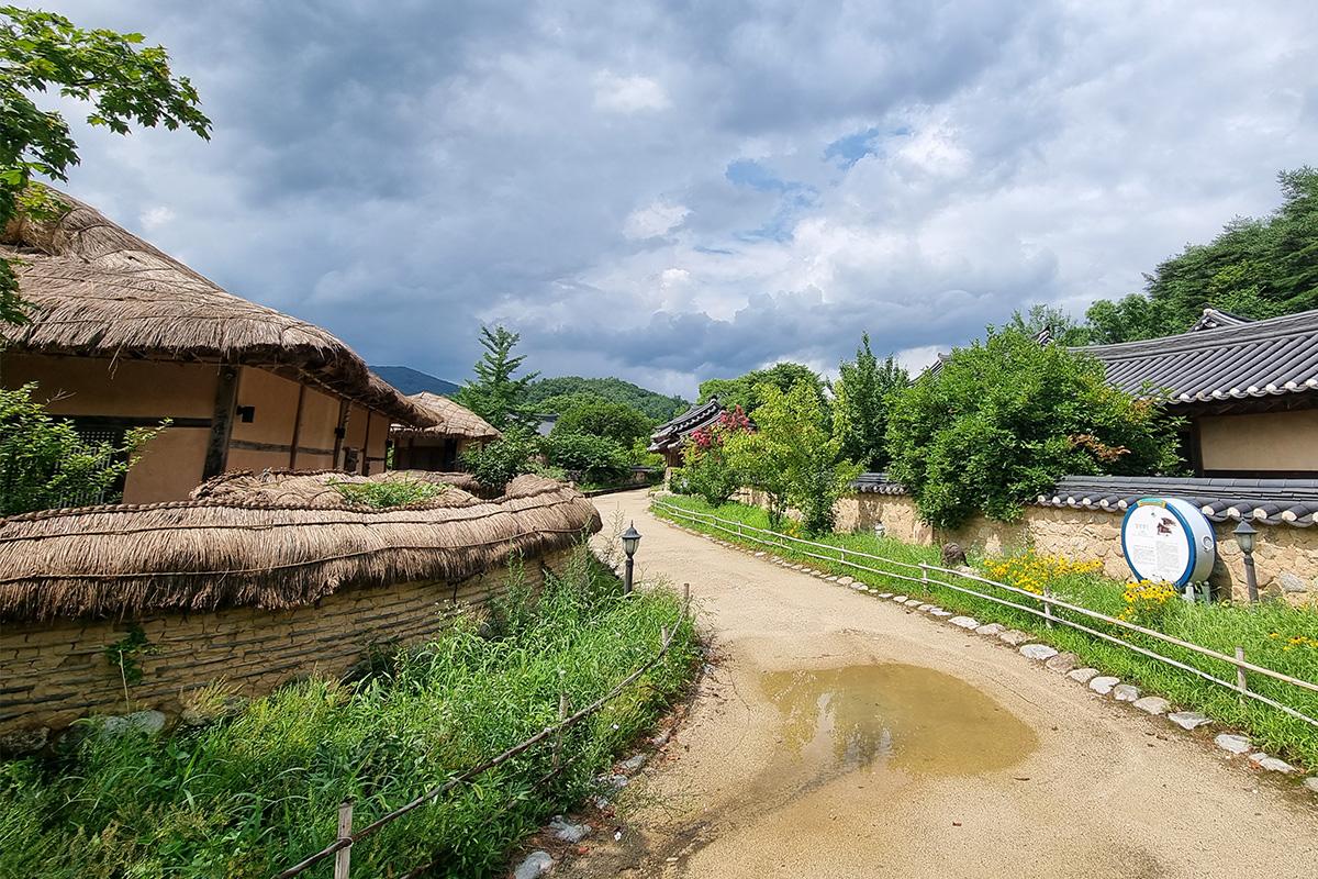 Vue panoramique du village Seonbi, mettant en valeur un pont en avant-plan et une forêt luxuriante.