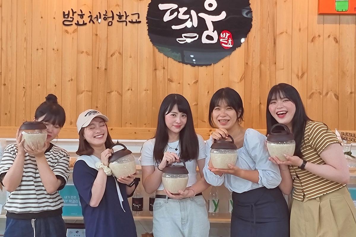 Participants au cours de fabrication de Makgeolli, tenant leurs pots de makgeolli fini dans une classe de démonstration.