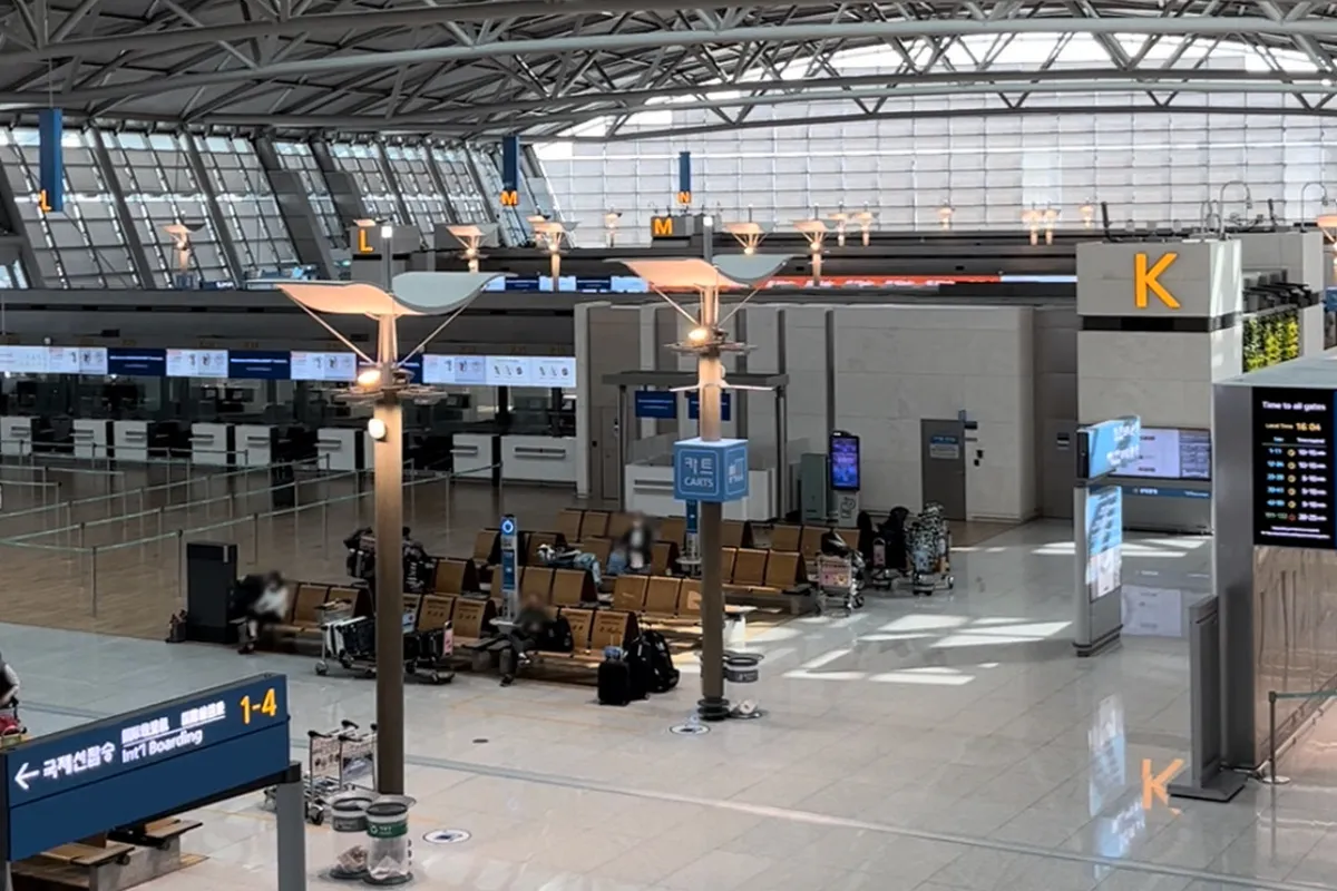 照片展示了仁川國際機場的航站樓的內部，可以看到航班出發的區域和幾位乘客在等候區。這張照片補充了韓國最新免籤政策的信息。