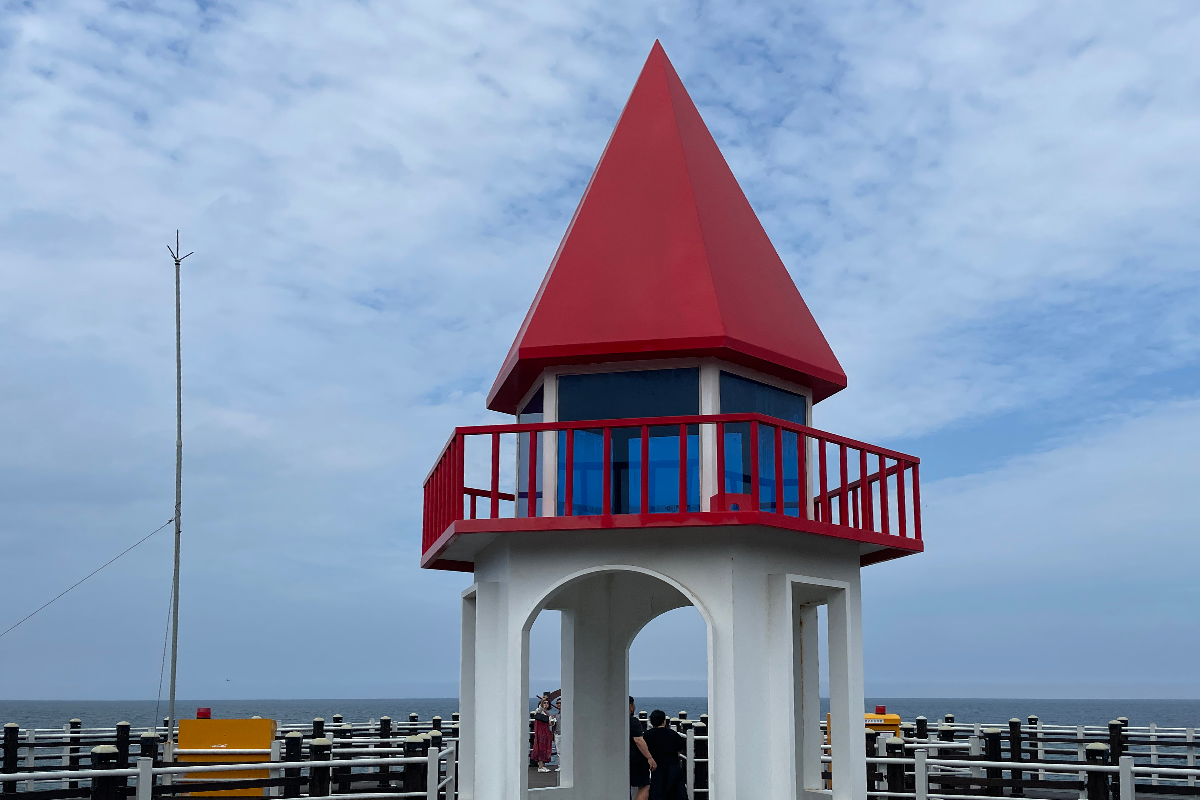 瞭望塔特寫，紅色尖頂和流水影像形成鮮明對比。