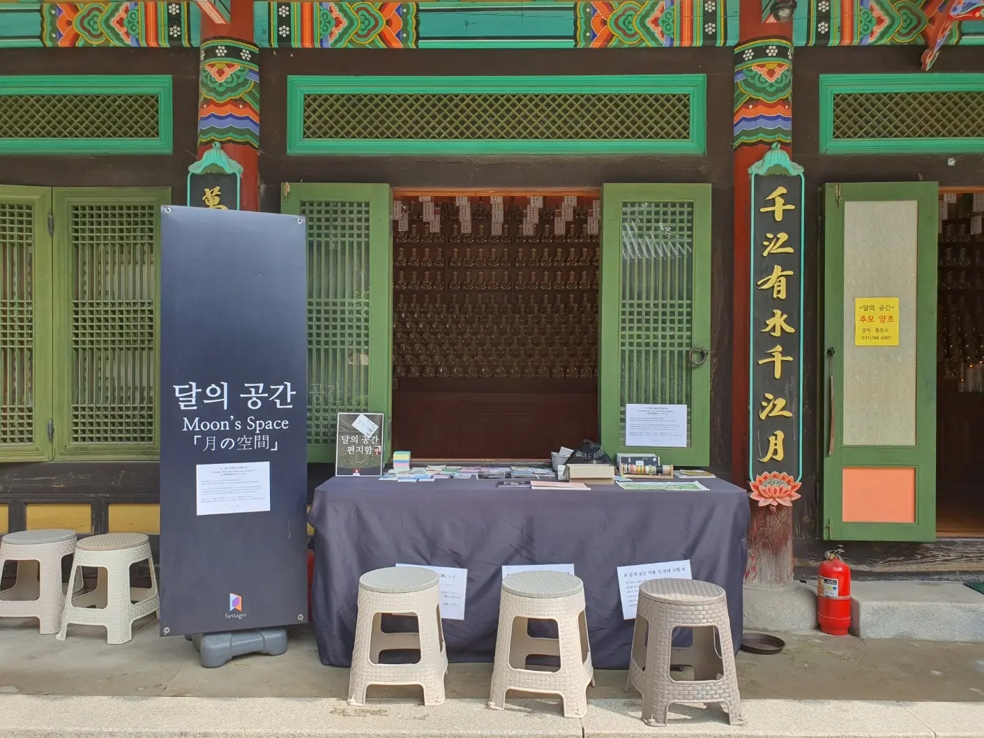 Không gian tưởng niệm cho ca sĩ Hàn Quốc ASTRO Moon Bin tại chùa Namhansanseong Gukcheongsa, bàn trưng bày với và tông màu nâu trắng, những chiếc ghế đẩu nhỏ.