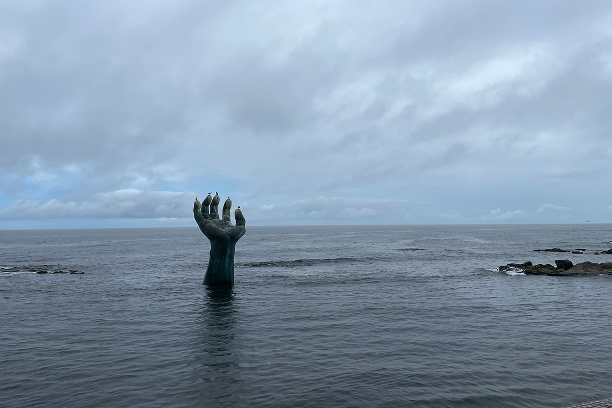 우산을 쓴 사람들이 포랩 해안에서 촬영한 모습, 일자로 놓여 있는 다리가 보입니다
