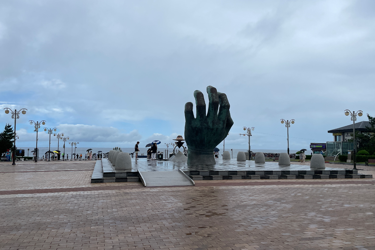 흐린 날씨 속 포항의 해변과 '상생의 손' 조각상, 구름이 잔뜩 끼어 있는 하늘과 함께 찍힌 풍경