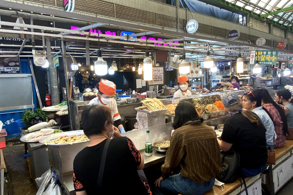 Гванжанг зах дахь хоолны газар, хүмүүс олон төрлийн ухаалаг хоол идэж байна.