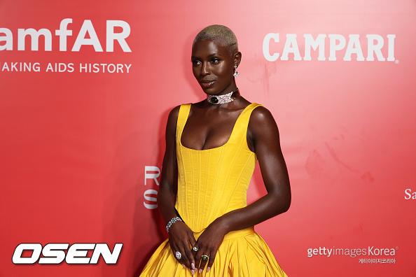 黄色のドレスを着た女性がレッドカーペットに立つ画像