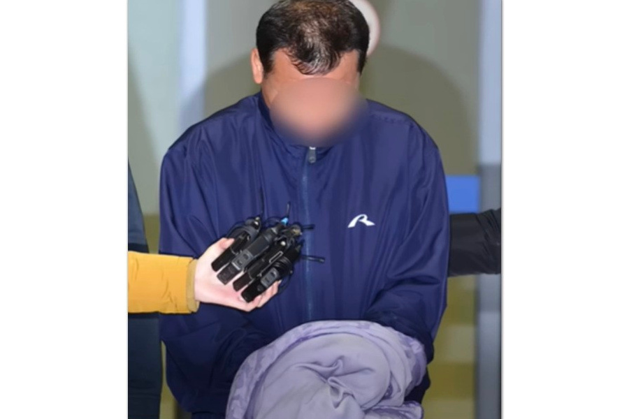 一名男子穿著運動服被拍到，雙手被拍，旁邊有麥克風指向他，顯然是被媒體包圍，這表現出一種拘捕的情況。這是捕捉到的真實警務操作場景。