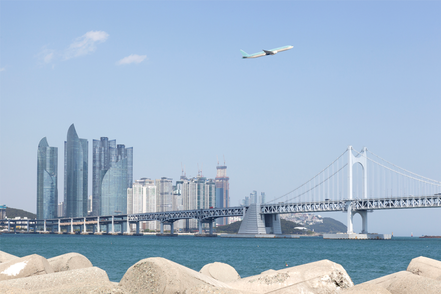 釜山海边景色，远处城市摩天大楼与近处的大桥，象征釜山现代与自然的完美结合，是韩国旅游中不可错过的城市风光。