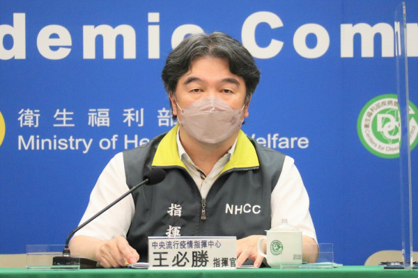 台湾中央流行疫情指挥中心关于入境检疫新制0+7，王必胜指挥官在记者会上发表讲话，背景为疫情指挥中心标志和卫生福利部标识，提供疫情最新资讯。